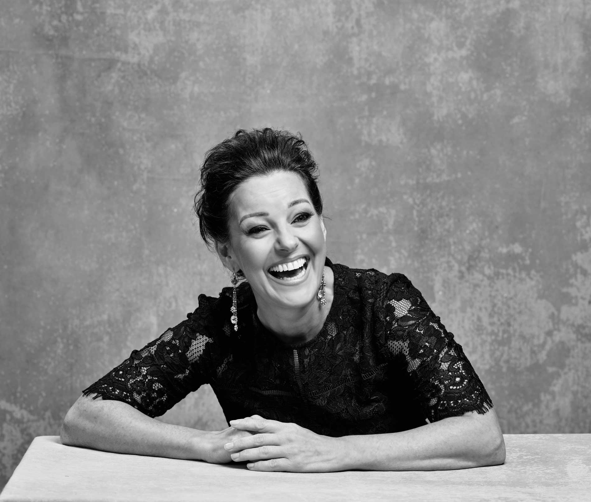 Portrait of Ruthie Henshall against a warm stone background